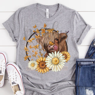 Highland cow with butterflies and flowers DTF Transfer screen print transfer soft ink ready to press peachy keen prints adorable cute pretty cow lover farm girl sunflowers daisies yellow beautiful butterflies on Bella canvas athletic heather gray short sleeve tshirt